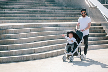 Father walking with a stroller and a baby in the city streets