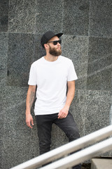 Hipster handsome male model with beard wearing white blank t-shirt space for your logo or design in casual urban style