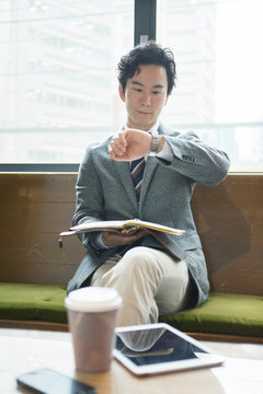 腕時計を確認する20代男性