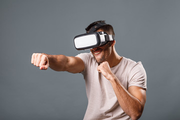 Young man with virtual reality glasses on gray background