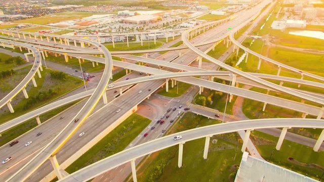 4K video of Houston Texas highway during golden hour with cars driving on the roads and overpass and the sunset and sky in the distance.