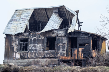 Burnt wooden house, black charred skeleton of a country house. Charred logs remained from the village house.