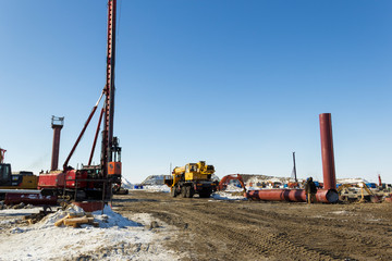 Drilling equipment, excavators, trucks build the sea port of Sabetta. Yamal, Russia. Winter, sunny