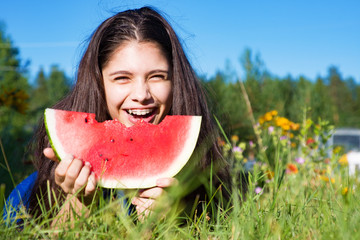 Girl eats watermelon outdoors in summer park, healthy food