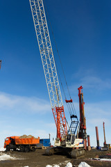 Drilling equipment, excavators, trucks and Construction cranes build the sea port of Sabetta. Yamal, Russia. Winter, sunny