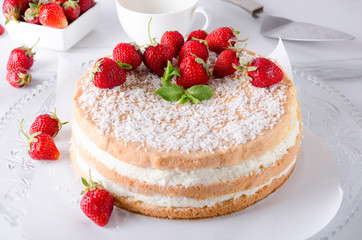Delicious traditional sponge cake, strawberry, cup of tea on the white marble table