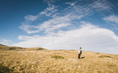 Obraz premium Beautiful summer sunny mountain landscape with a clear blue sky with clouds background. Crimean mountains. young man is running small paraglider. Learning paragliding. Launch a paraglider