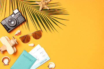 travel accessories and tropical leaves on a colored background top view.