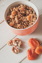 closeip top view on A bowl of porridge with wallnuts and dry apricot on the white wodden table. Orthodox chistmas kutya.  Orthodox chistmas celebration dish.