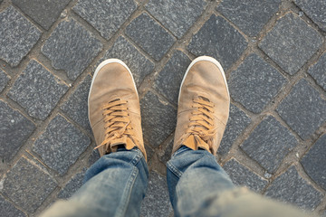 POV of male gumshoes on paving slabs, view from above