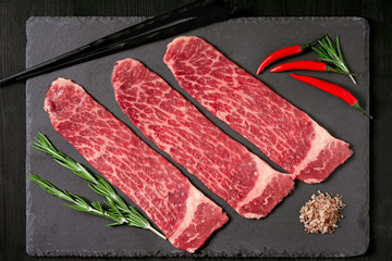 Pieces of raw marble beef black Angus for grilling on a stone Board on a dark background