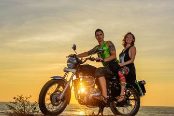 Fototapeta na wymiar Romantic picture with a couple of beautiful stylish bikers at sunset. Handsome guy with tatoo and young sexy woman enjoy themselves in motorbike trip.