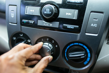 Car driver turning air conditioner.