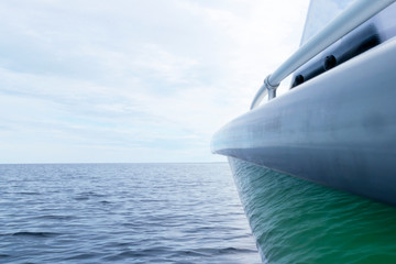 Naklejka premium Side view Speeding fishing motor boat with drops of water. Blue ocean sea water wave reflections with fast fishing yacht. Motor boat in the blue ocean. Ocean yacht. Sunset at the sailboat deck