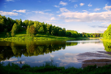 Reflection of the sky in the blue of a calm lake. Forest, illuminated by the sun, on the opposite Bank. Russia