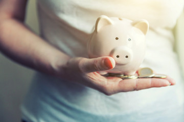 Female woman hands holding pink piggy bank and putting money Euro coin. Saving investment budget...