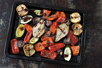 Baked pumpkin, zucchini, paprika, pear, apple, blue onion with herbs and spices on a baking sheet. Baked mix vegetables and fruits. Vegan lunch