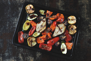 Baked pumpkin, zucchini, paprika, pear, apple, blue onion with herbs and spices on a baking sheet. Baked mix vegetables and fruits. Vegan lunch