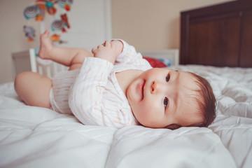 Portrait of cute adorable Asian mixed race baby girl four months old lying on bed in bedroom. Natural emotion face expression. Childhood diversity lifestyle