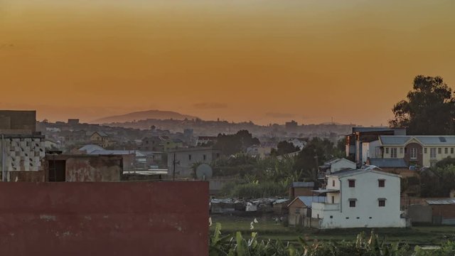 Antananarivo, Madagascar romantic time lapse. Last rays of sunlight hit the rooftops with hazy hills on the background