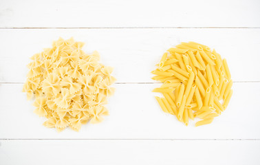 various types of pasta on a white wooden table. Italian cuisine concept, food ingredients. Flat lay. Top view, copy space