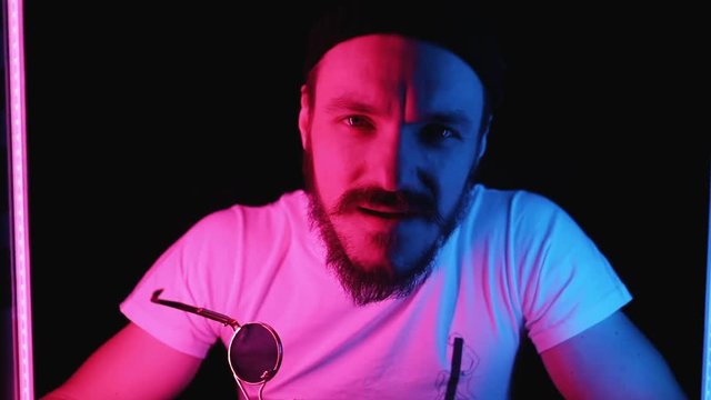 Close-up portrait of daring young man looking straight at camera with indignant facial expression. Cool guy chilling at the party.