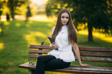 Obraz premium Young female teacher with tablet outside. Modern teacher in the park. Woman wears glasses