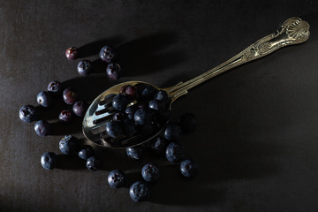 Low key blueberries on a vintage spoon and dark grey background. Stylish contemporary fresh image of healthy superfood fruit. Horizontal.