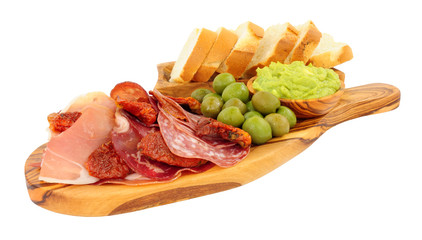 Gran antipasto snack selection on an olive wood serving board with salami, cured meat slices and a bowl of crushed avocado dip isolated on a white background