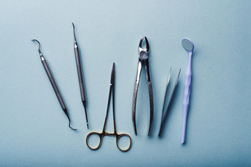 Different dental steel instruments on light blue background