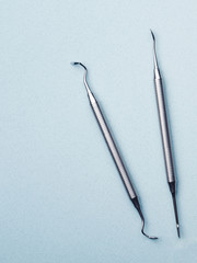 Metal dental tools on light blue background