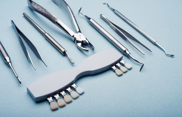 Different dental steel instruments on light blue background