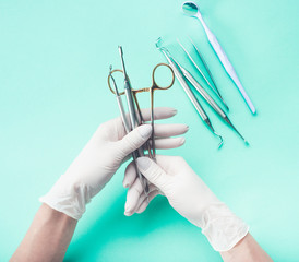 Hands in gloves holding medical tools on light background