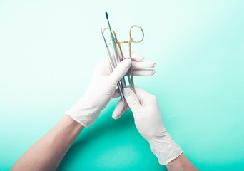 Hands in gloves holding medical tools on light background