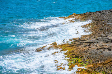 Small waves break on the rocks on the coast.