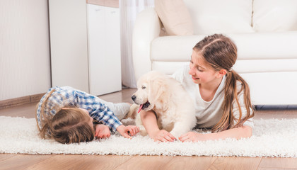 sisters lying together on carpet with cute retriever puppy