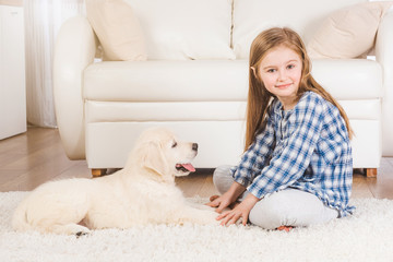 Smiling little girl sitting with fluffy retriever puppy at home