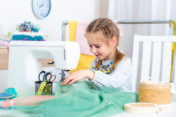 Little girl using sewing machine to make crafts in the workshop