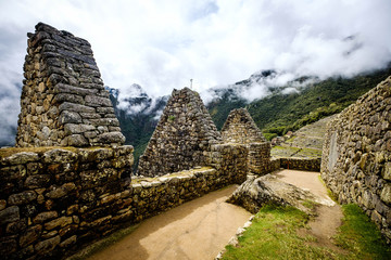 Fototapeta na wymiar Sunshine breathtaking view of Machupicchu stone anchient walls and temple among mountains covered with clouds