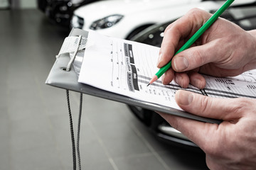car service, repair, maintenance concept -  mechanic writing to the clipboard at workshop...