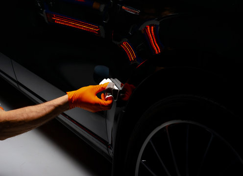 Car polish wax worker hands polishing car. Buffing and polishing vehicle with ceramic. Car detailing. Man holds a polisher in the hand and polishes the car with nano ceramic. Tools for polishing