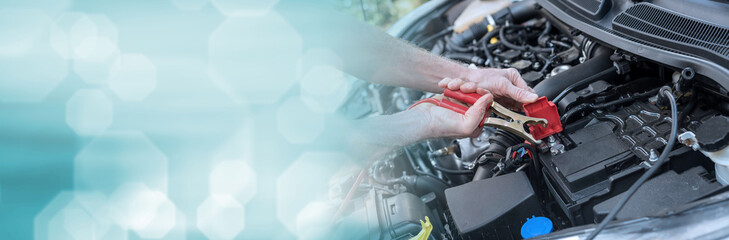 Hands of car mechanic using car battery jumper cable. panoramic banner