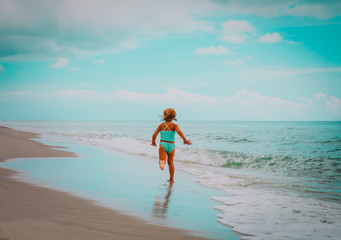 happy little girl run play with waves on beach