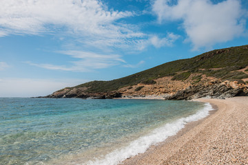 wild beach in sardinia, italy with clear blue sea and rocks