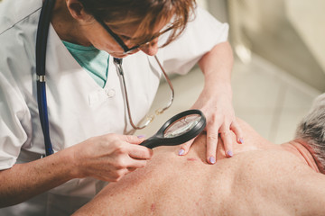 Dermatologist examining the skin of a patient