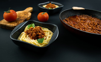 Spaghetti bolognese on a plate on wooden dark background. Italian cuisine concept, food ingredients. Close up view