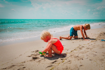 littlegirl and boy play with sand on beach