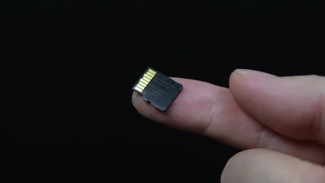 Hand with Micro SD card isolated on white background.