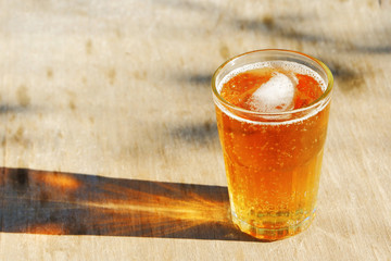 Close up on a pint glass of amber Pale Ale beer, casting a shadow on a old wood table.