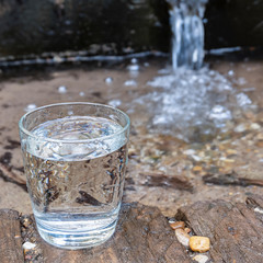 A glass of spring water in nature.